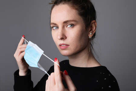 Young woman wearing medical face mask, studio portrait.の写真素材