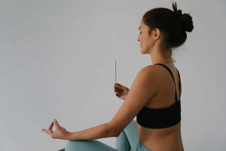 Young woman sits in yoga asana and practicing meditation, breathing, relaxing.