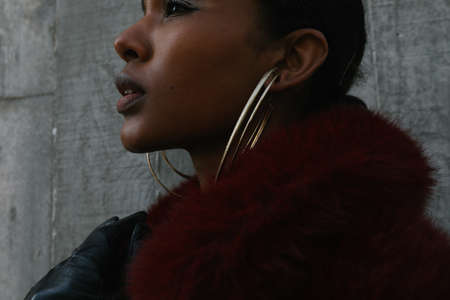 Cropped portrait of young beautiful African American woman poses on gray wall.の写真素材