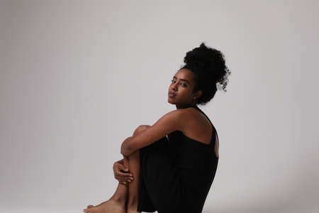 Beautiful black afro young woman with curly hairstyle posing in the studio.の写真素材