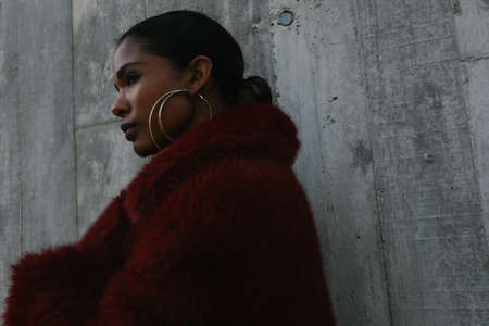 Portrait of young beautiful African American woman poses on gray wall.