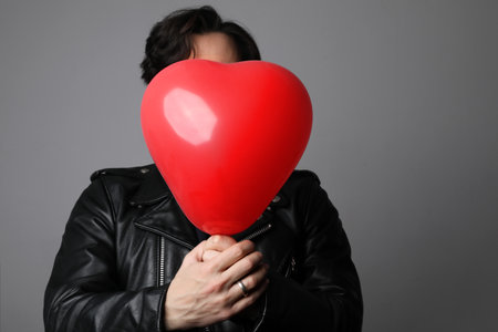 Love. Headshot of handsome young spanish man with inflating balloon.の写真素材