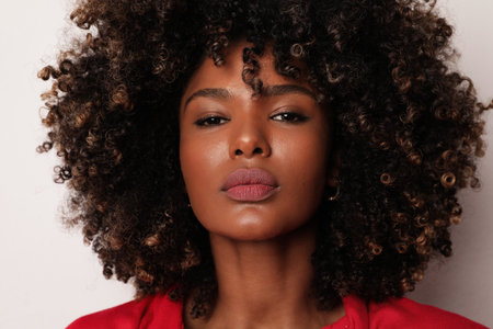 Headshot of African American young woman with curly hair over white background.の写真素材