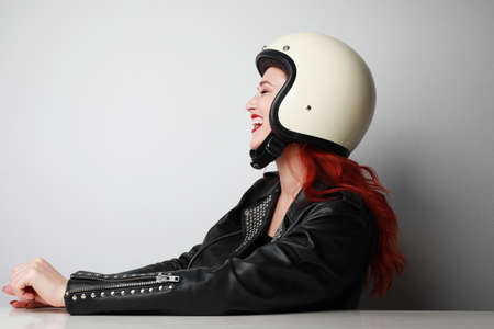 Profile portrait of happy young biker woman wears helmet and leather jacket.の写真素材