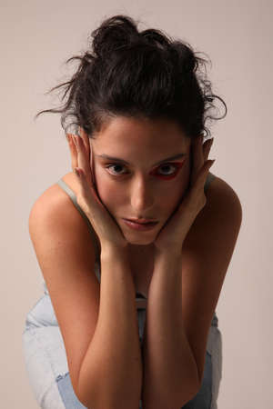 Pretty young woman touches her face posing over white background. Isolated.の写真素材
