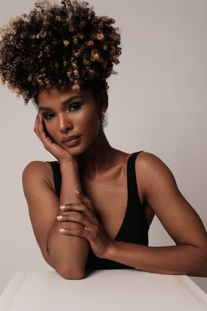 Beautiful African American woman with curly hair posing on white. Vertical.