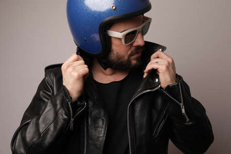 Biker man posing in leather jacket and blue motorcycle helmet. Isolated.