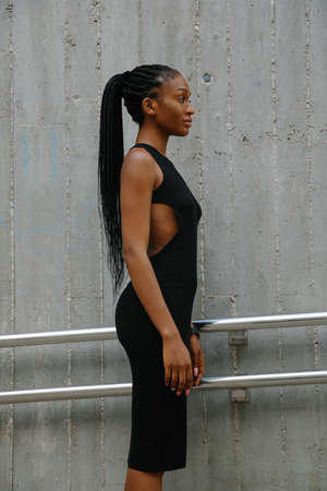 Vertical side photo of young beautiful woman with braids posing outdoor.の写真素材