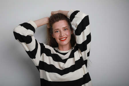 Smiling young woman looking at the camera, posing on withe background. Vetical.