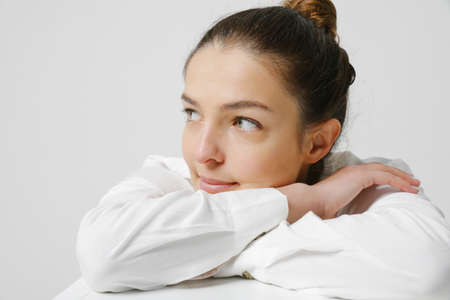 Joyful woman dressed in casual shirt, shows beauty, poses against white wall.の写真素材