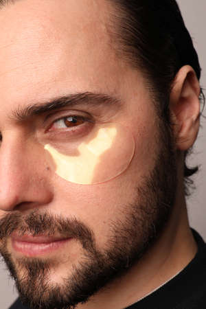 Cropped close-up portrait of bearded man wearing eye patches isolated. Vertical.