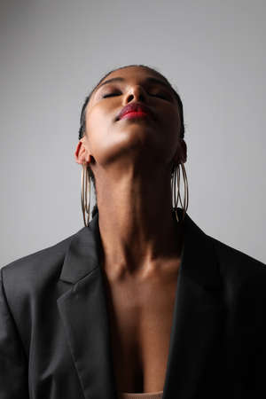 Portrait of African young woman with braids posing on white wall. Vertical.の写真素材