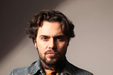 Headshot of young bearded man looking at the camera. Isolated on white wall.