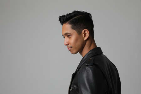 Side portrait of handsome Asian man posing near white wall. Freelance. Mock up.