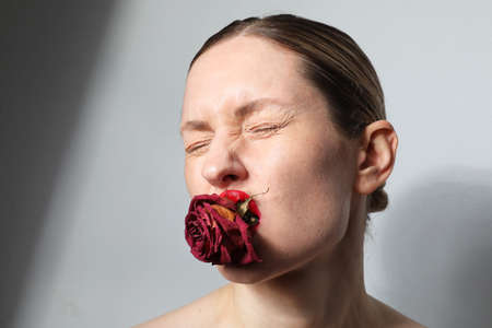 Close-up portrait of young woman with dry rose holds in lips. Beauty skin.の写真素材