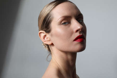 Beauty face. Young woman with fresh glowing skin and red lips posing at studio.の写真素材