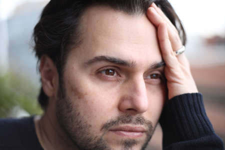 Headshot of sad and melancholic bearded young man posing outdoor. Mock-up.の写真素材