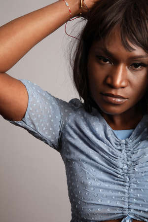 Close-up portrait of African American young woman wears blue dress posing indoorの写真素材