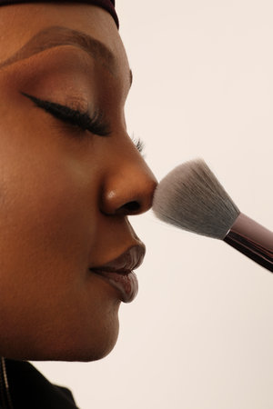 Close-up of beautiful muslim young woman retouch make-up on her face. Vertical.の写真素材