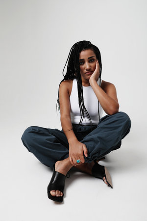 African American young woman with long dark braids, posing at studio. Mock-up.