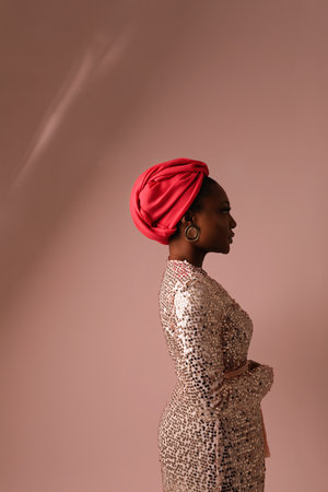 Muslim black woman wearing sparkling dress and hijab posing on pink background.の写真素材