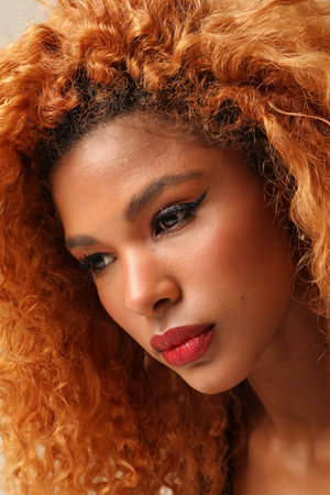 Close-up of young beautiful woman with afro hairstyle posing on the white wall.の写真素材
