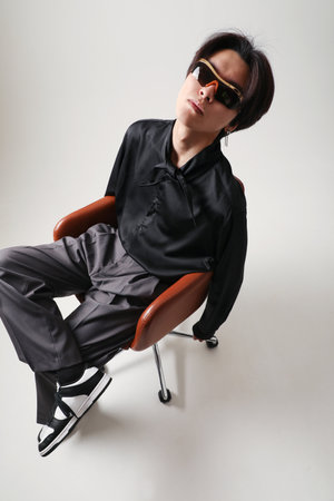 Confident young Asian man posing indoor sitting over white background. Mock-up.の写真素材