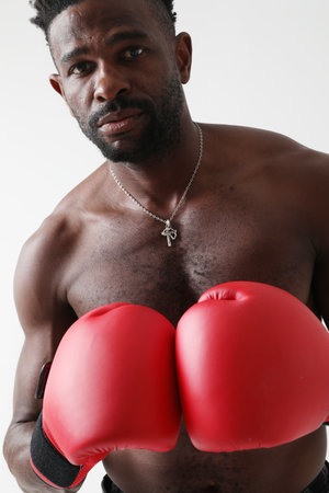 Athletic young man with naked torso and good physique boxing with red gloves.の写真素材