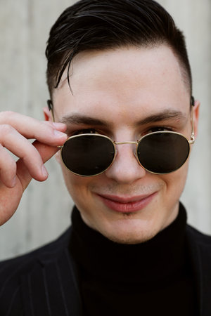 Handsome stylish hipster young man wears sunglasses posing outdoor. Vertical.の写真素材
