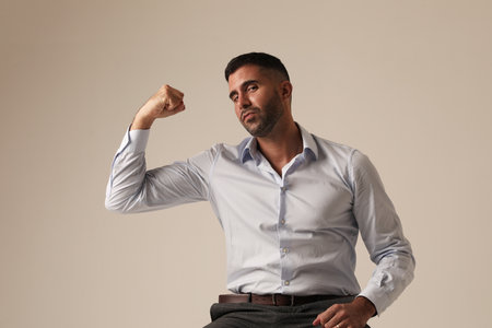 Headshot of bearded young man showing his biceps and looking at the camera.の写真素材