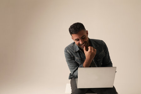 Bearded young man working with laptop while sitting indoor. Mock-up.の写真素材