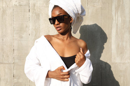 Headshot of African American young woman wrapped in white towel posing outdoor.の写真素材