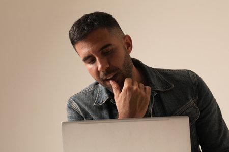 Close-up of young Indian guy working online from home, using laptop. Mock-up.の写真素材