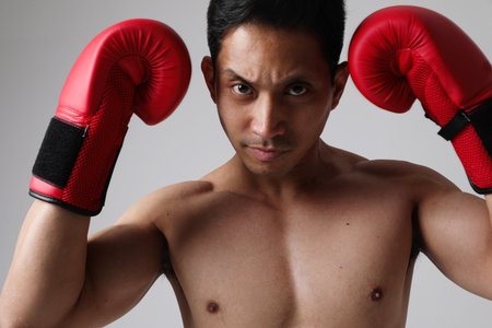 Attractive fitness angry young asian man play boxing with gloves. Mock-up.の写真素材