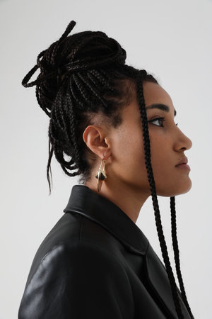 Side-view of young African American woman with dark braids, posing indoor.