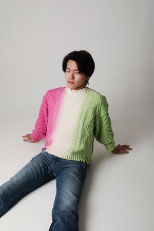 Confident young Asian man sits down on the floor over white background. Mock-up.の写真素材