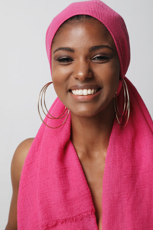 Beautiful and happy young woman with traditional turban posing on white wall.の写真素材