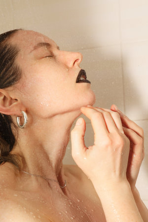 Side portrait of beautiful and young woman taking shower. Healthy lifestyle.の写真素材