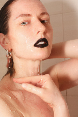 Beautiful and young woman taking shower. Healthy lifestyle. Vertical.の写真素材