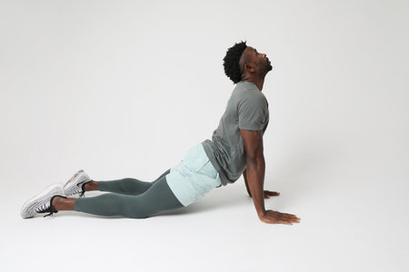 Athletic young man doing muscle stretching exercises over grey background.の写真素材