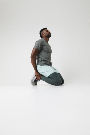 Athletic young man doing muscle stretching exercises indoor. Vertical mock-up.の写真素材