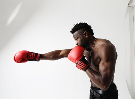 Athletic young man with good physique body condition boxing with red gloves.の写真素材