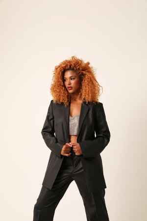 Beautiful young African American woman wears black suit posing indoor. Vertical.の写真素材