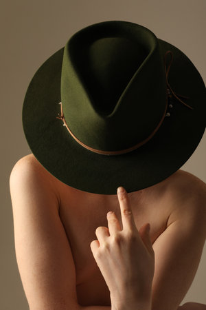 Vertical close-up of attractive young woman wearing green hat looking down.の写真素材