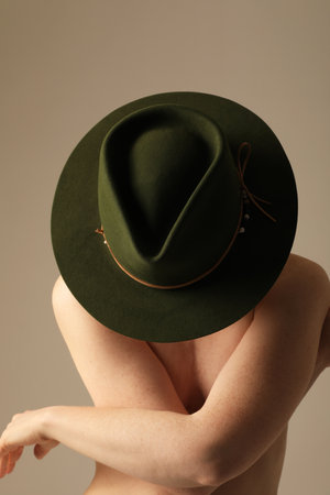 Vertical close-up of gorgeous woman wearing green hat posing indoor. Mock-up.の写真素材