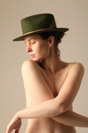 Vertical close-up of gorgeous young woman wearing green hat posing indoor.の写真素材
