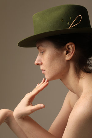 Vertical side portrait of confident young woman wearing green hat posing indoor.の写真素材