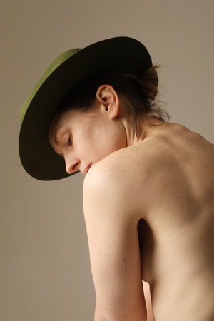 Vertical close-up of confident young woman wearing green hat posing indoor.の写真素材