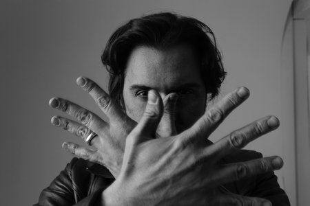 Close-up of handsome man showing hands isolated on white wall. Black and white.の写真素材