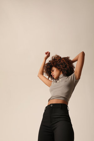 Beautiful African American young woman with curly hair dancing over white wall.の写真素材